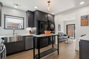 Une cuisine moderne avec des meubles de couleur sombre, des appareils électroménagers en acier inoxydable et un îlot central.