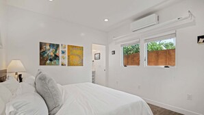 A bedroom with a bed, white walls, and artwork. - NEW Rustic Villa – 2BD, 2BA Close to Beach and Everything! (Santa Barbara)