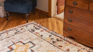 A room with a dark blue chair, a wooden dresser, and a patterned rug. - Aspen Room Serene Retreat at Columbine (Silverton)