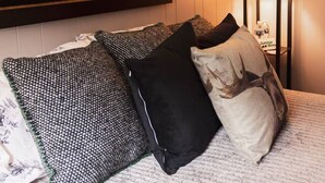 Hotellihuone, jossa on sänky, kehystetty peuranpään taideteos ja yöpöytä, jossa on lamppu.