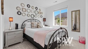 Een slaapkamer met een bed, nachtkastjes, een dressoir, een raam met uitzicht en een wand versierd met ronde spiegels.