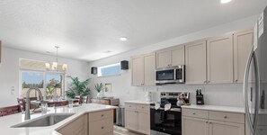Une cuisine moderne dotée d’un îlot central, d’appareils électroménagers en acier inoxydable et de meubles de couleur claire.