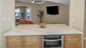 A modern kitchen with a central island, built-in oven, and a ceiling light fixture. - Family Friendly Retreat near Clearwater Beach. (Safety Harbor)