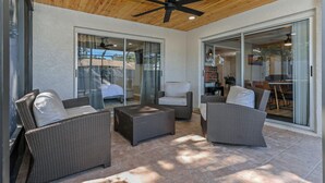 An outdoor patio area with wicker furniture, a ceiling fan, and sliding glass doors leading to an indoor space. - Family Friendly Retreat near Clearwater Beach. (Safety Harbor)