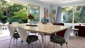 A dining area with a wooden table, white chairs, and a red sofa. - Private Coastal Sanctuary, Next to the beach! (Coastlands)