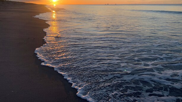 A beach with gentle waves and a sunset in the background. - Private Coastal Sanctuary, Next to the beach! (Coastlands)