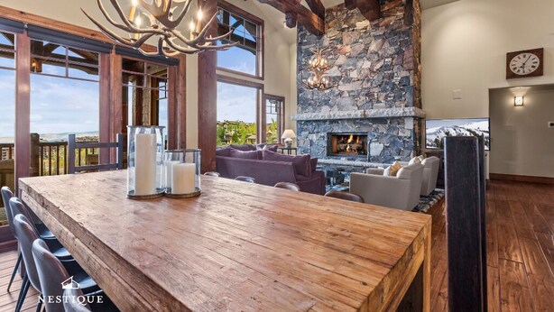 Una cocina amplia con chimenea de piedra, vigas de madera y ventanas grandes con vistas panorámicas.