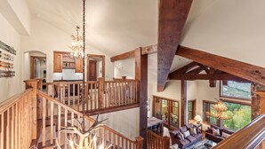 Interior de madera de varios niveles con una escalera, un candelabro y vistas al exterior.