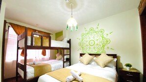 Een hotelkamer met stapelbedden, een bed met decoratieve wand, een nachtkastje en een hanglamp.
