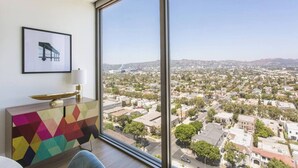 A room with a large window offering a city view, a colorful geometric-patterned cabinet, and a framed picture on the wall. - Visit LA in Ultra Luxury with Breathtaking Views (Beverly Hills)