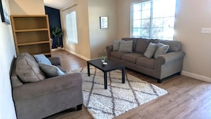 A living room with a sofa, a coffee table, and a bookshelf.