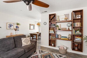 A living room with a gray sofa, wooden bookshelves, and a ceiling fan.