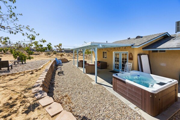 A residential property with a covered patio, a hot tub, and outdoor seating.