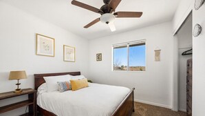 A bedroom with a bed, a ceiling fan, a window, and framed artwork on the wall. - Starlight Ranch with Hot tub, Fire pit & BBQ! (Joshua Tree)