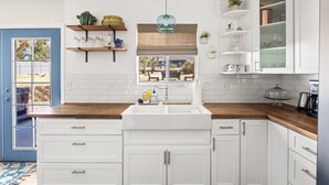 A kitchen with white cabinets, a wooden countertop, a built-in sink, and a window with a view of the outdoors. - Starlight Ranch with Hot Tub, Fire Pit & BBQ! (Joshua Tree)
