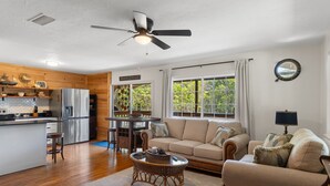 A spacious living area with a kitchen, dining table, sofa, and a ceiling fan. - Peaceful Waterfront Escape on Withlacoochee • Private Dock, Old Florida Charm (Yankeetown)