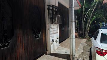 A gated entrance with a wooden door, a metal gate, and a white car parked outside.