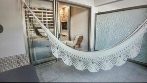 A hammock on a balcony with a chair and a stone wall in the background. -  Available Oct.22-28th Luxury at its finest!!! 1-Bedroom, 1300 sq ft Condo, (Cabo San Lucas)
