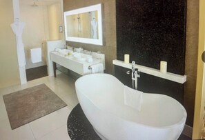 Une salle de bain moderne avec une baignoire sur pieds, un grand miroir et un meuble-lavabo doté de deux vasques.