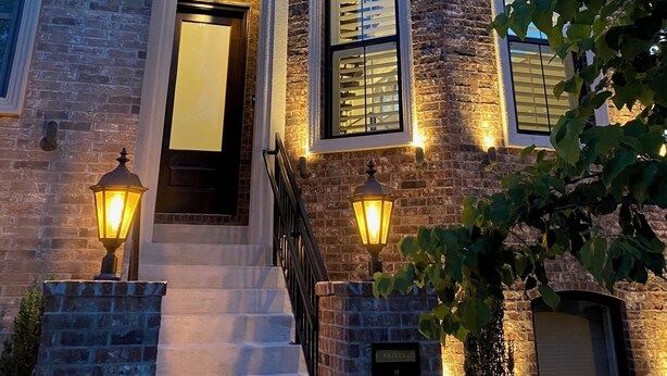 A multi-story brick building with a central entrance, a staircase, and multiple windows with external lighting. - Uptown Brownstone - 1 Block off Downtown Square (Bentonville)