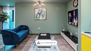 Een moderne woonkamer met een blauwe bank, een bijzettafeltje en een schilderij aan de muur.