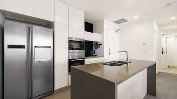 A modern kitchen with a stainless steel refrigerator, built-in oven, microwave, and a large island with a sink.