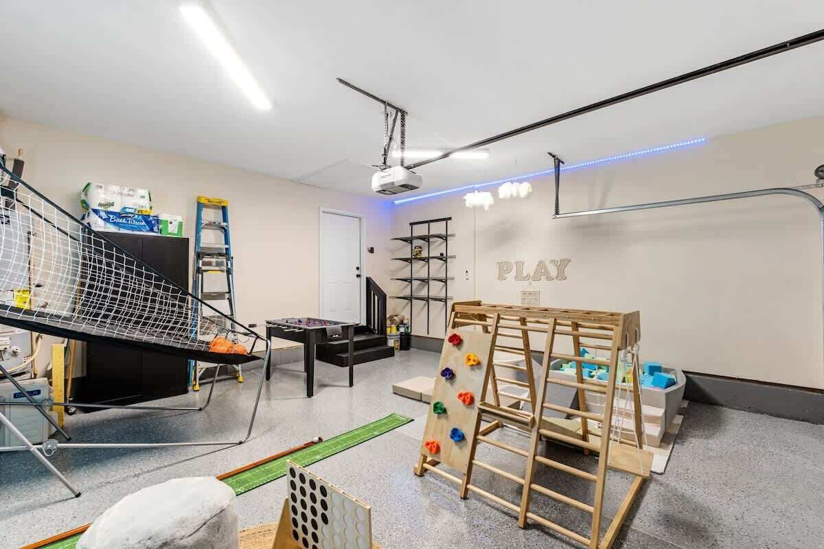 Une salle de jeux équipée d’un mur d’escalade, d’une table de ping-pong et d’étagères remplies de jouets.