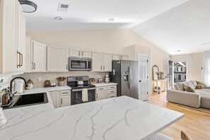 A modern kitchen with white cabinetry, a marble countertop, and a built-in oven.