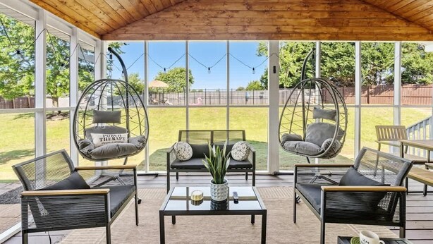 Un espacio de estar al aire libre cubierto, con sillones colgantes, sofás y una mesa de centro.