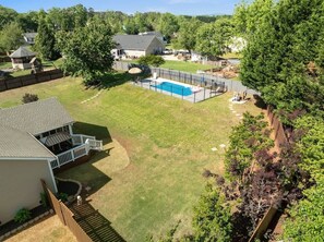 A residential backyard with a swimming pool, a fenced patio area, and a house with a deck. - Private GEM in SC-Pool, Huge Porch, Fenced Yard (Greer)