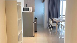 Una cucina moderna con forno a microonde, frigorifero e zona pranzo con tavolo e sedie.