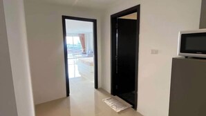 Un corridoio con vista su un balcone, una porta nera e un forno a microonde su un mobiletto.
