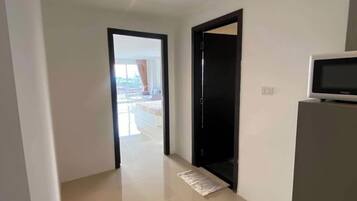 Un couloir donnant sur un balcon, une porte noire et un four à micro-ondes posé sur un meuble.