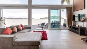 Un amplio salón con un gran ventanal corredera que da a un balcón con vistas a un cuerpo de agua.