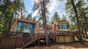A cabin with a wooden deck, a staircase, and a large window. - The Cub House: Mountain Home w/ Hot Tub, Pool Table, 5 bed/4ba, Fireplace, Woods (Ruidoso)