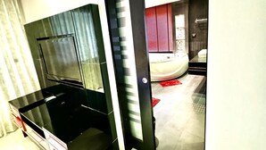 A modern kitchen with a black countertop and a glass door leading to a bathroom with a red towel rack. - L08 Penthouse Suite, Modern Condo On Bangla Road (Patong)