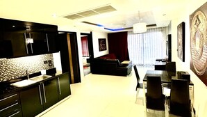 A modern living room with a dining area, featuring a kitchen with black cabinets and a tiled backsplash. - L08 Penthouse Suite, Modern Condo On Bangla Road (Patong)