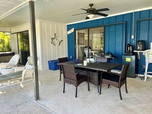 Un patio abrité, équipé d’une table, de chaises et d’un ventilateur de plafond.