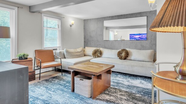 Una sala de estar moderna con un sofá, sillones, una mesita de centro y un televisor.