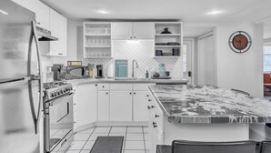Una cocina moderna con armarios blancos, horno empotrado, microondas y fregadero.