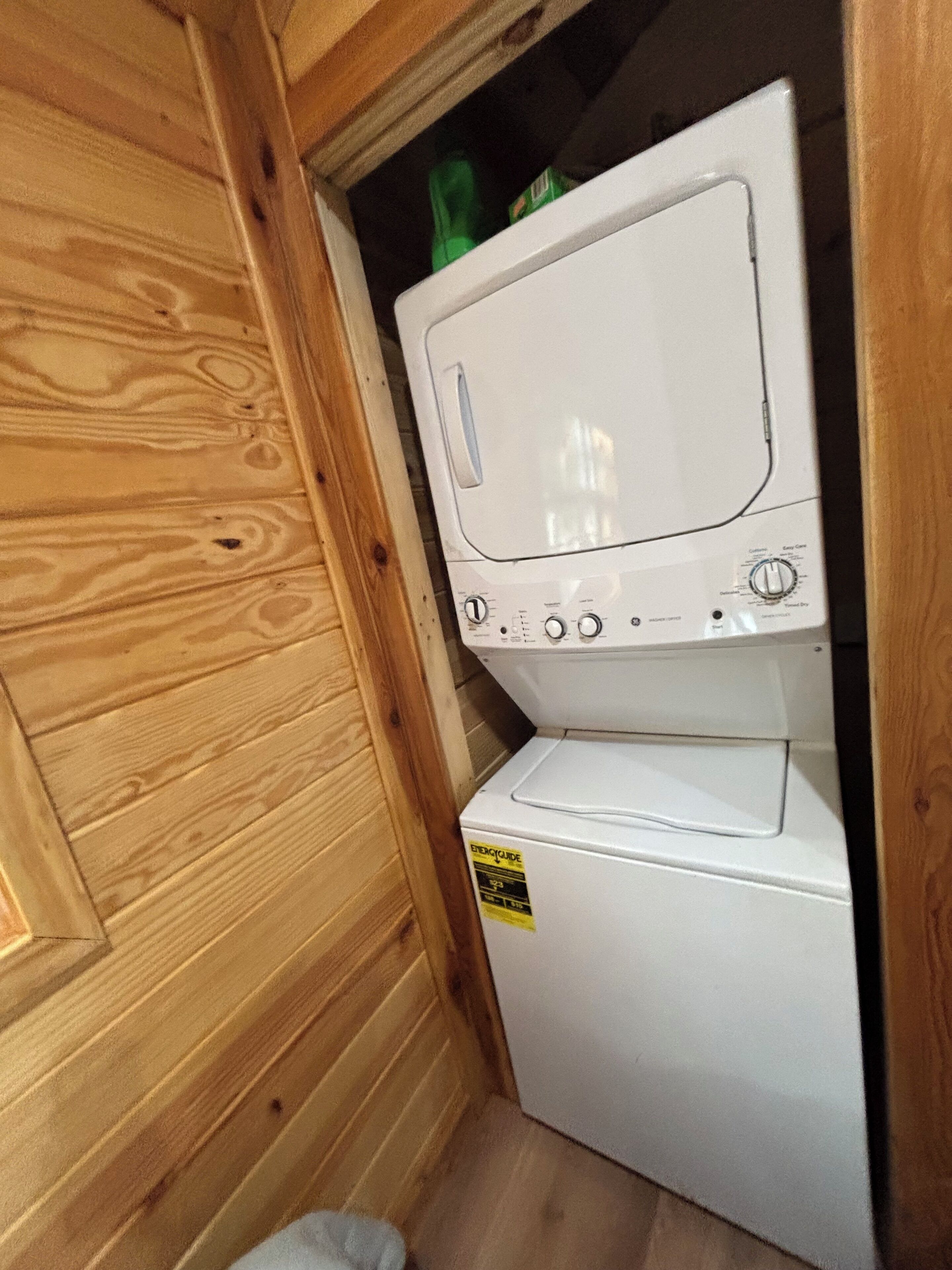 A compact, white laundry machine in a wooden utility room.