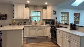 Una cucina moderna con mobili bianchi, un'isola centrale, un forno a microonde e un piano cottura.
