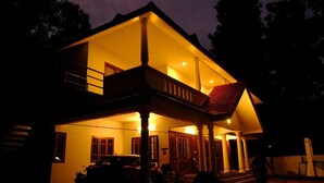 A two-story house with a balcony, a porch, and a car parked in front. - River Meadows  (Tiruvalla)