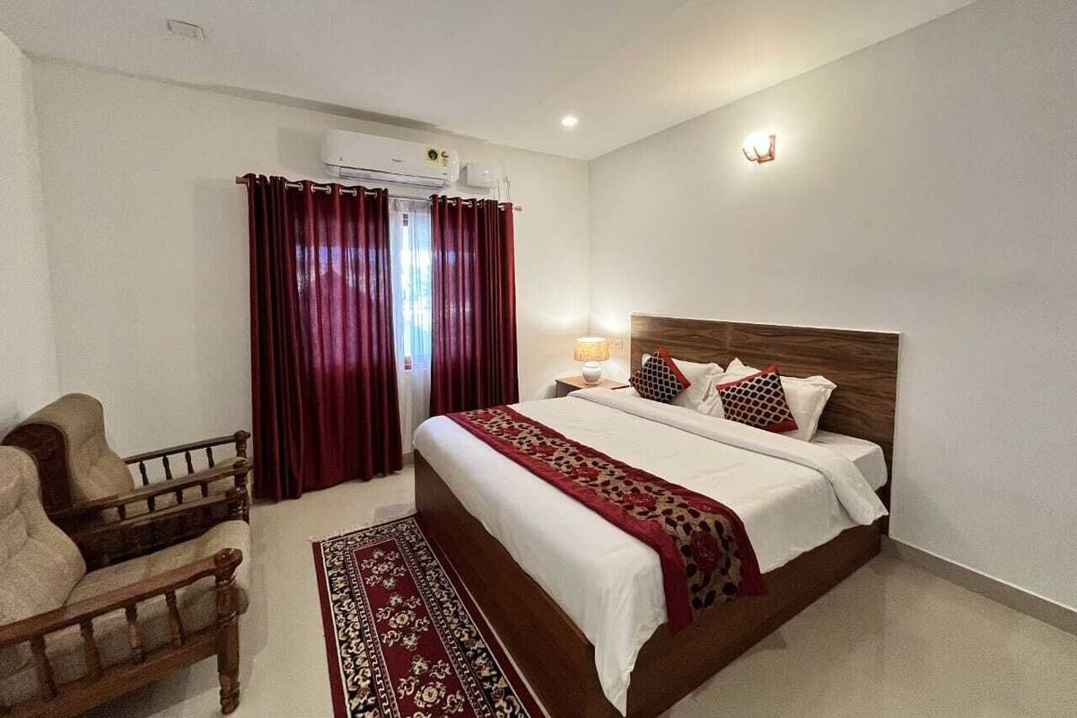 A bedroom with a bed, a chair, a rug, and a window with curtains.