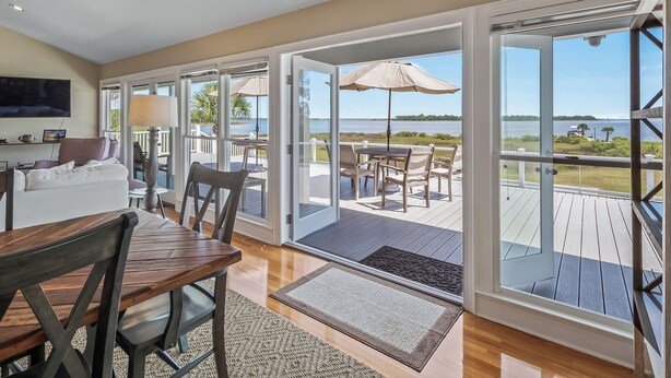A spacious room with a large sliding glass door leading to an outdoor deck with a view of the water. - Bay Breeze - Waterfront with Boat Dock, Helipad! (Panacea)