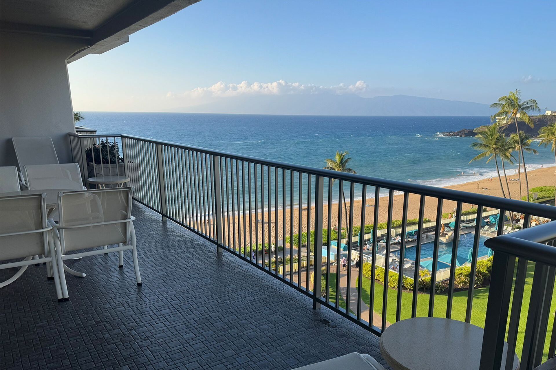 Un balcon avec vue sur l’océan, un espace piscine et une plage.