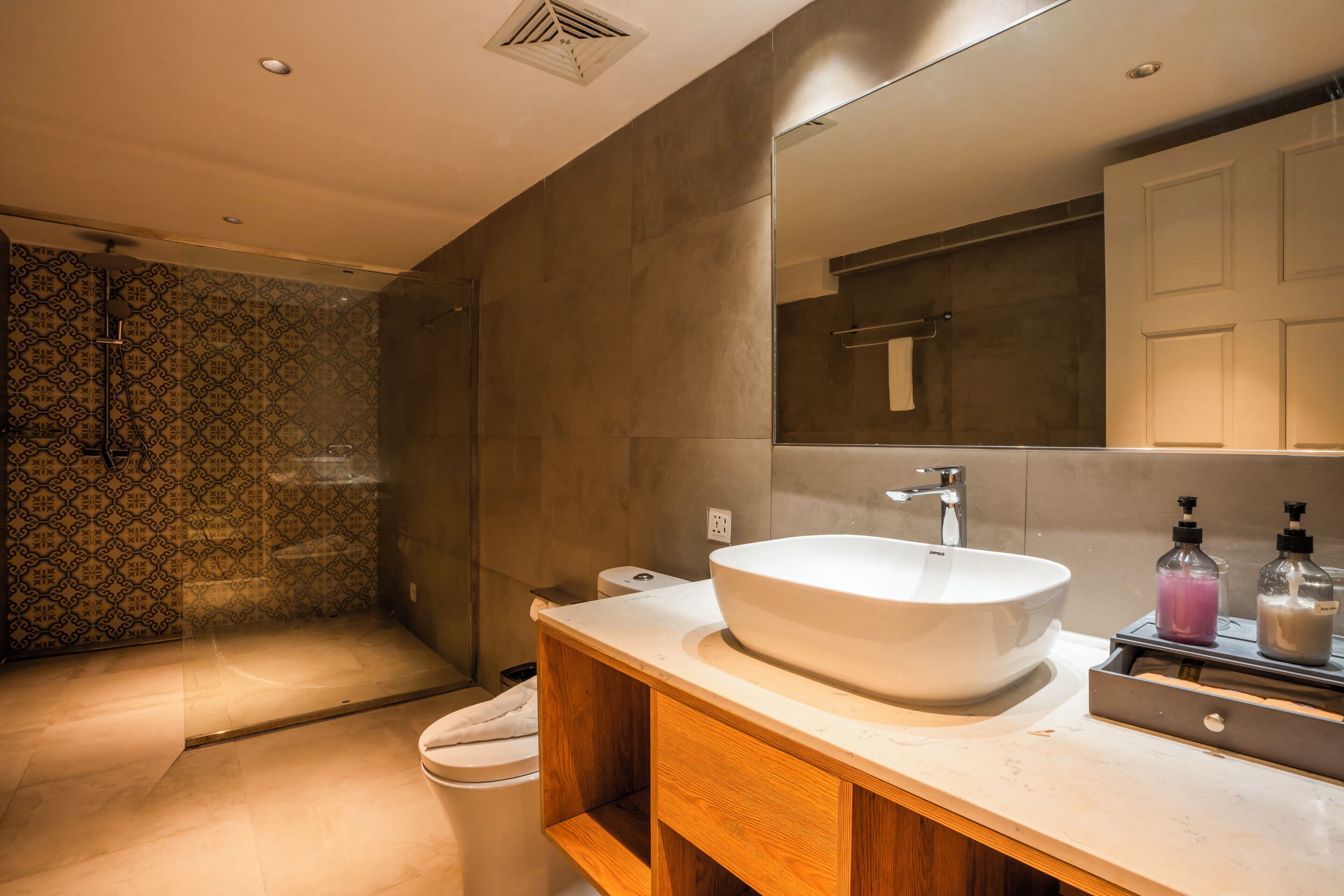 A modern bathroom with a large sink, mirror, and shower.