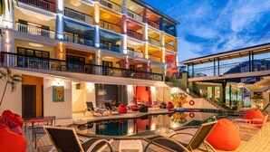 Um hotel com vários andares, área de piscina, espaço para sentar ao ar livre e escadaria que leva aos andares superiores.