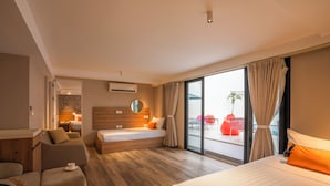 Quarto de hotel com cama, sofá, escrivaninha e uma janela grande.