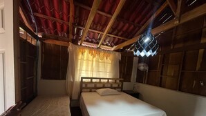 Una habitación con dos camas individuales, cabeceros de madera, un ventilador de techo y una ventana con cortinas.